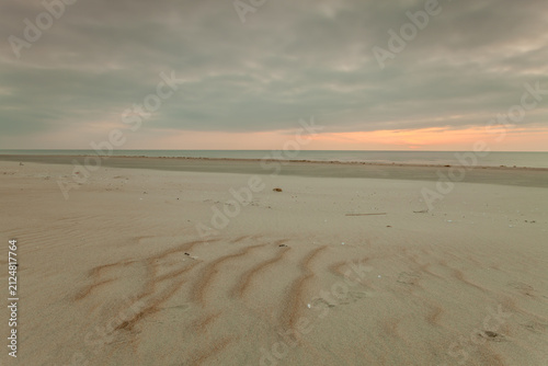 Фотография Empty sandy beach at sunset under cloudy sky