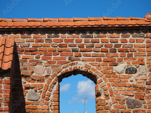 Blue sky and a window opening in a red wall