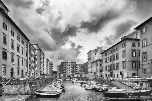Boats moored in the canals of Livorno, Italy under clouds
