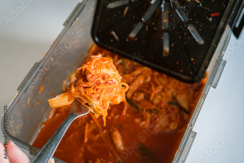 Obraz na plátne Kimchi spooned from container with fork in healthy homemade Korean cuisine