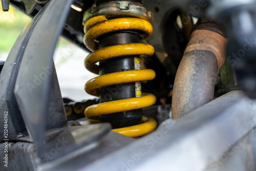 Yellow coil spring on motorcycle rear suspension close up