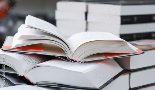 stack of books, close up. Open book on the table in library. Back to school concept. Open book on table with blur bookshelf background