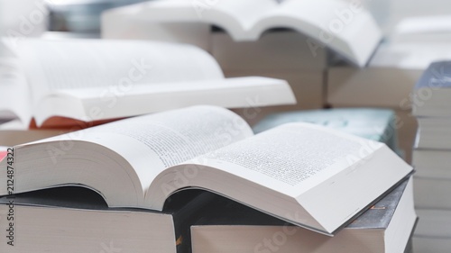 stack of books, close up. Open book on the table in library. Back to school concept. Open book on table with blur bookshelf background