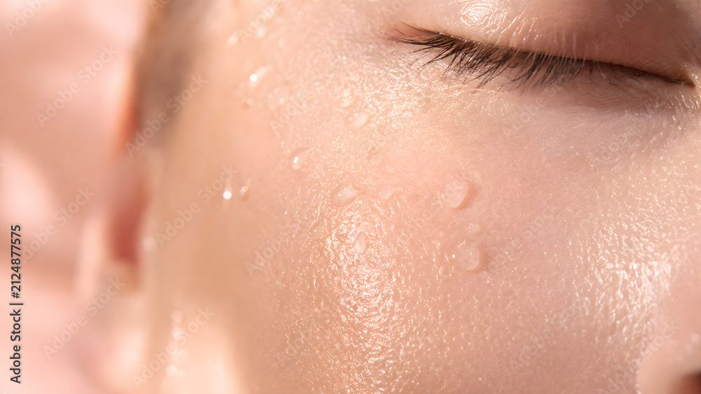 Fototapeta premium Extreme closeup of a persons face with water droplets on glowing, dewy skin