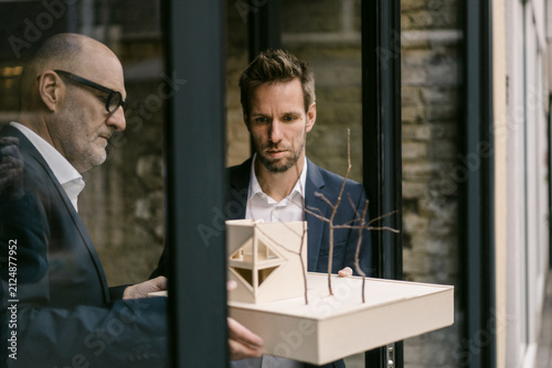 Senior and mid-adult businessman with architectural model