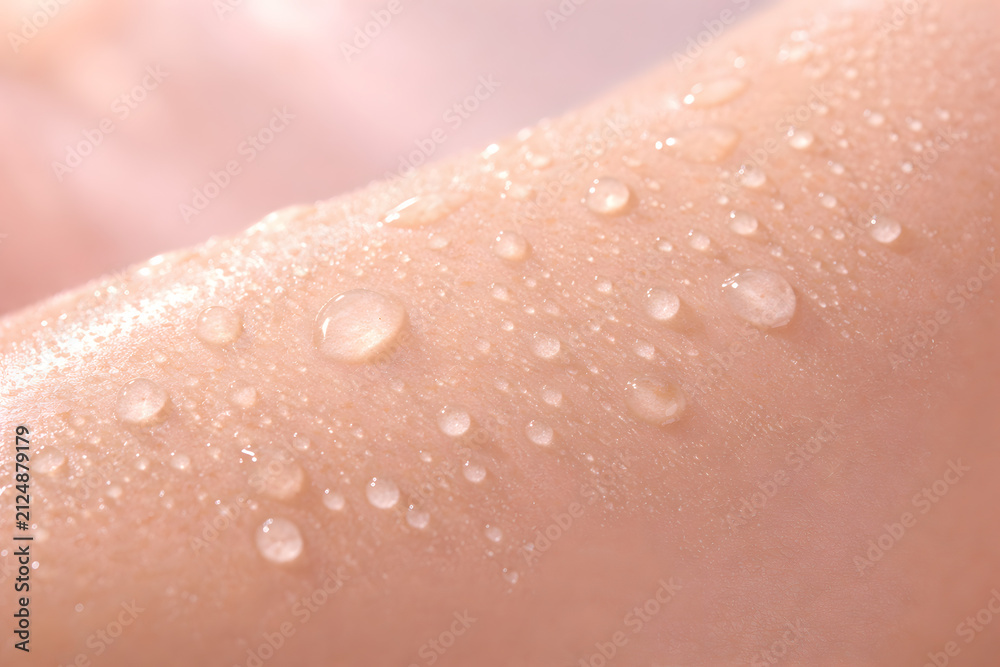 Fototapeta premium Closeup of clear water droplets on smooth human skin, highlighting hydration, freshness, and skincare