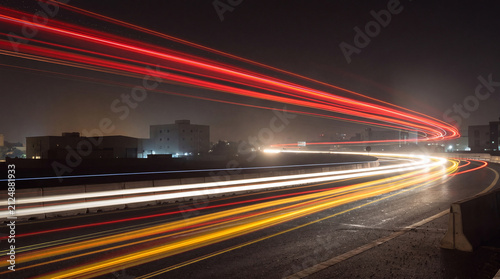 Dynamic long exposure photograph of colorful car light trails on a curved highway at night.