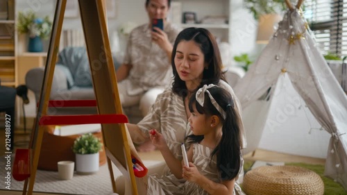 Asian mother or father teaching daughter doing homework on laptop at home. Parents supporting girl during summer break and back to school season.Concept of child education and family relationship life