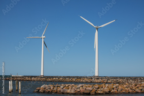White Wind Turbines Standing Near the Sea on a Coastal Landscape