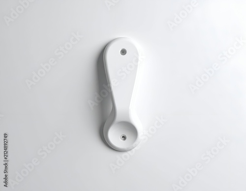 White, spoon-shaped, wall-mounted object with a hole for hanging, placed against a white backdrop