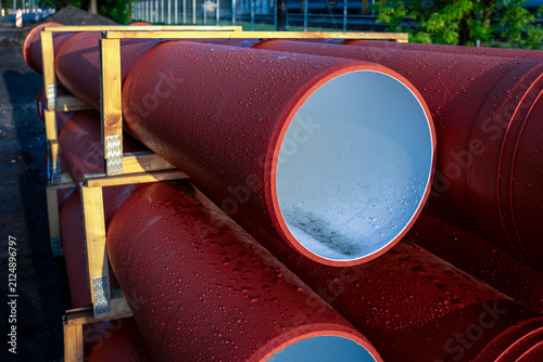 Obraz na płótnie Rain-Covered Orange Sewer Pipes Secured in Wooden Storage Racks