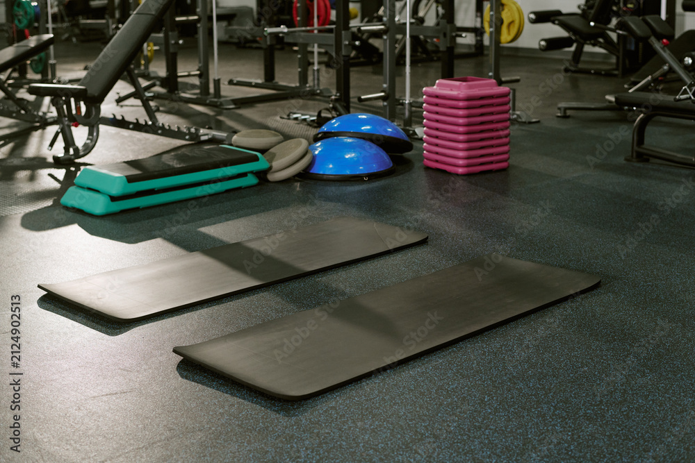Fototapeta premium Empty fitness mats and workout equipment on gym floor, preparing for training session. Perfect for sports club marketing and fitness class promotion