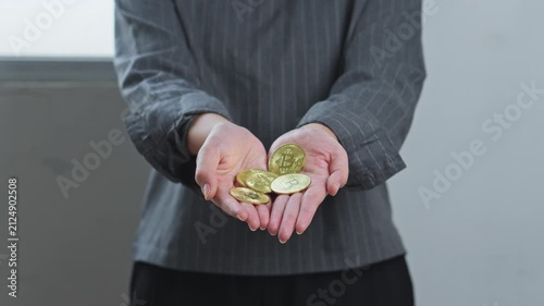Woman cupping her hands as gold bitcoin coins fall into them for representing cryptocurrency earnings