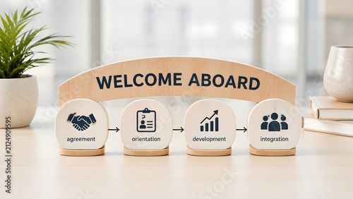 Wooden blocks displaying welcome aboard message and employee onboarding stages on bright office desk