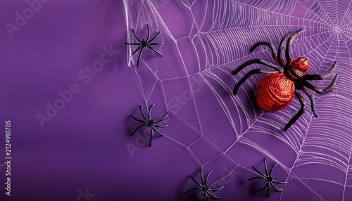 Close-up of big red and black spiders decoration on a web on dark purple background with copy sapce