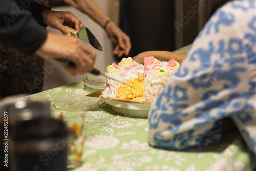 Hands serving a slice of birthday cake at family gathering
