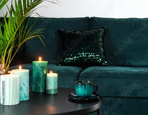 Teal candles & sequined pillow adorn a plush teal sofa, with coffee & palm