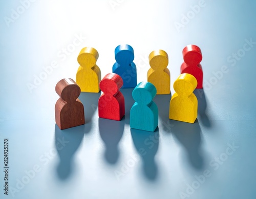 Wooden figures of varied colors representing a diverse group on a light blue surface