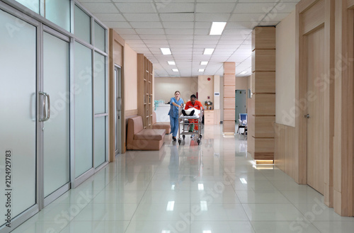Two healthcare worker are hurriedly transferring a patient on a stretcher in a  well-lit hospital hallway during the day, illustrating urgency and teamwork in medical care.