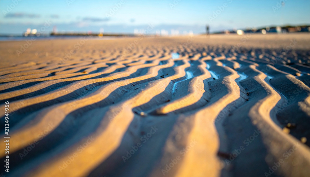 Obraz premium Golden sunset light on beach sand ripples texture with blurred background