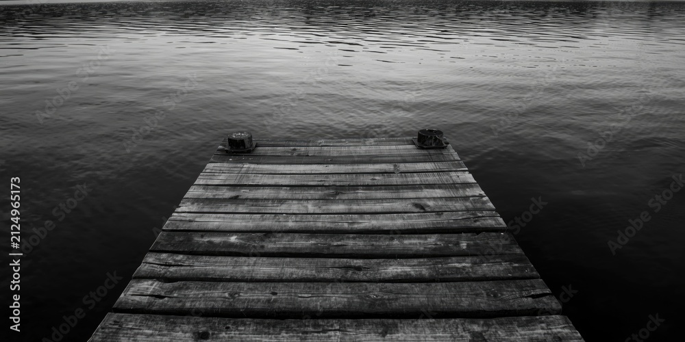Obraz premium Wooden Dock Extending Into Calm Water in Black and White