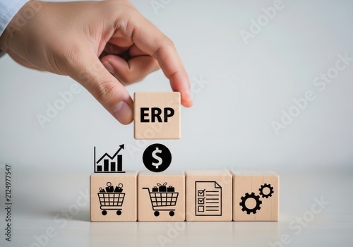 Hand placing a wooden block with erp text on top of other blocks featuring business process icons