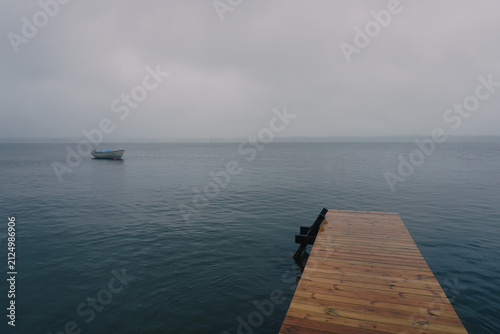 Wooden pier and boat on foggy lake