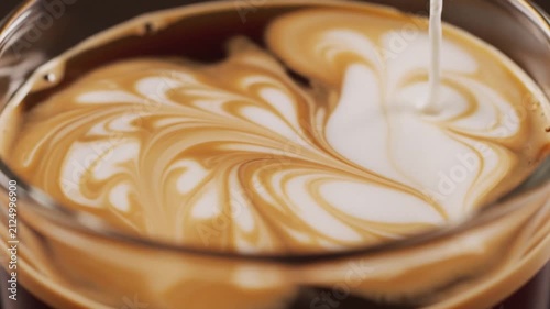 Milk pouring into cup of black coffee macro view.