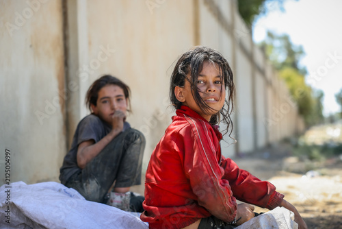 фотографія Thoughtful poor children sitting near a wall