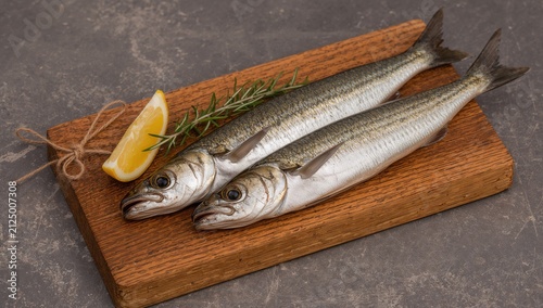 Fresh Whole Fish Presented on a Wooden Cutting Board with Lemon and Rosemary