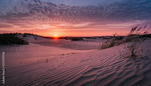 Sunset over Sand Dunes with Wavy Patterns and Cloudy Sky