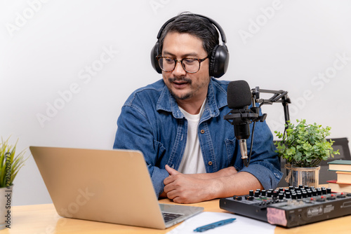 Fotografie A young male freelancer records a podcast episode at his home office setup using modern audio gear