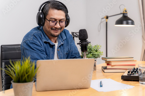 Fotografie A young male freelancer records a podcast episode at his home office setup using modern audio gear