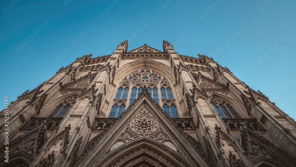 Fototapeta premium Gothic Cathedral Facade Reaching Skyward Against Clear Blue Sky