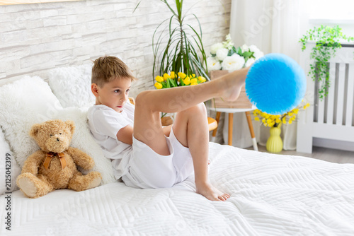Cute little preschool child, cute blond boy, playing in bed with many teddy bears, handmade amigurumi toys, enjoying toy game