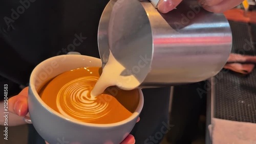 Barista pouring milk to craft detailed winged heart latte art