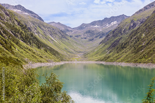 Little Tibet at the end of Zillergrund dam Lake with with water reflections and the surrounding mountain ridges