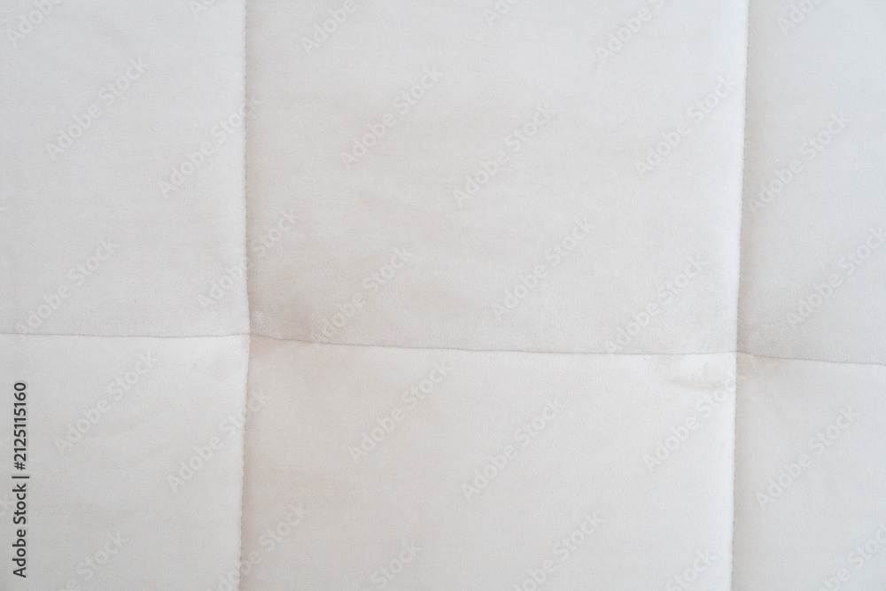 Fototapeta premium Close-up of a light cream tufted fabric upholstery texture with stitched square seams