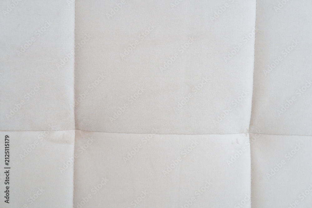 Fototapeta premium Close-up of a light cream tufted fabric upholstery texture with stitched square seams