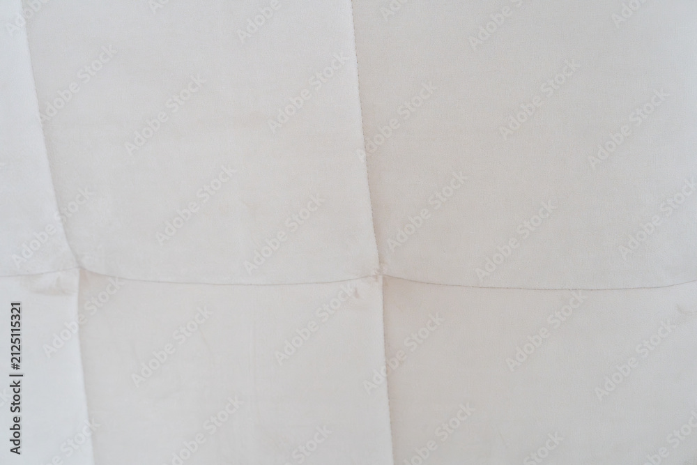 Fototapeta premium Close-up of a light cream tufted fabric upholstery texture with stitched square seams