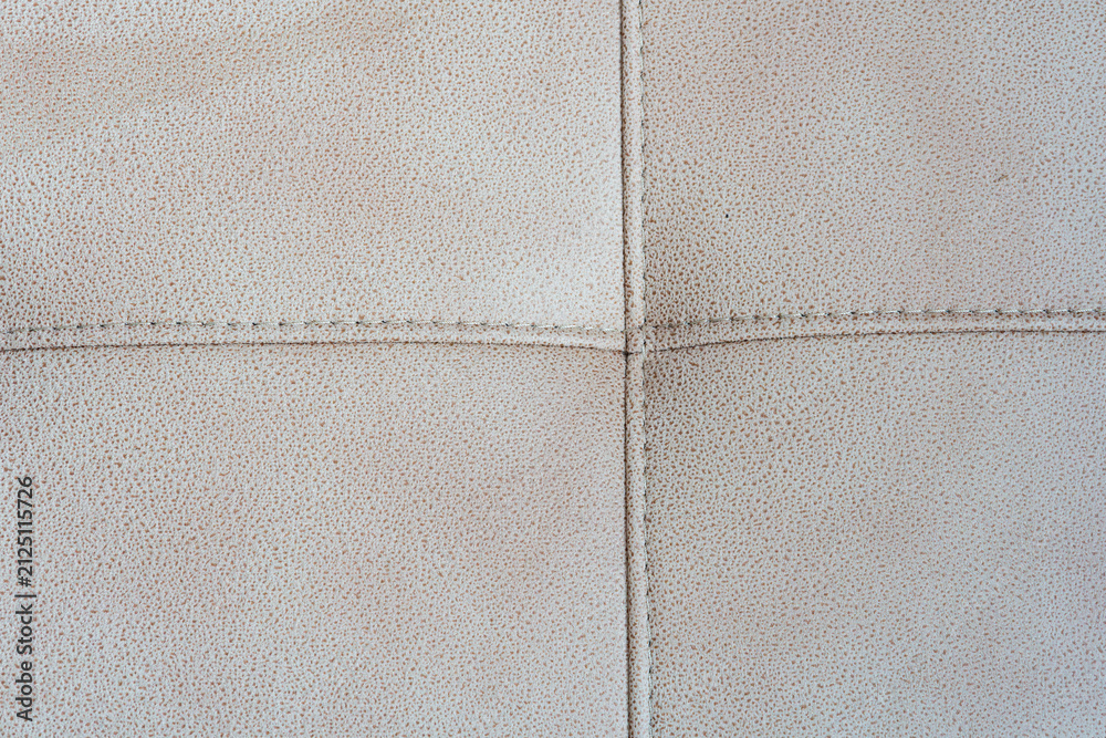 Fototapeta premium Close-up of a beige tufted leather upholstery texture with stitched crossed seams