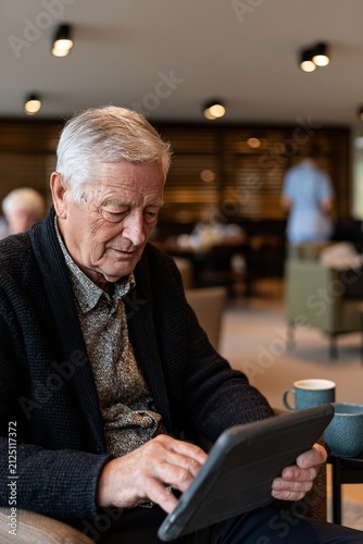 an older, spry man who is looking intently at the screen of a tablet PC set up in front of him