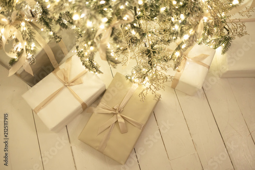 Christmas presents in white boxes lie under the tree, light background, festive atmosphere