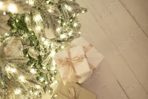 Christmas presents in white boxes lie under the tree, light background, festive atmosphere