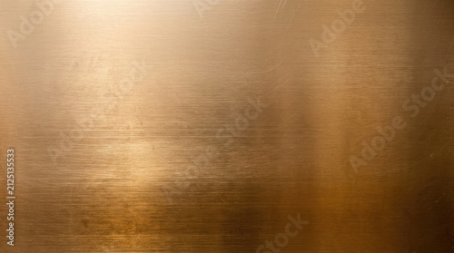 A smooth, polished copper surface reflects light, creating a gradient from dark brown at the bottom to a warm, golden hue at the top. Subtle streaks and scratches add texture to the metallic surface.