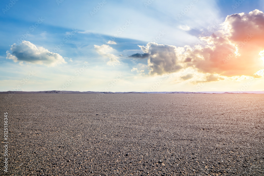 Obraz premium Vast empty gravel desert plain under a dramatic sky with bright sunbeams