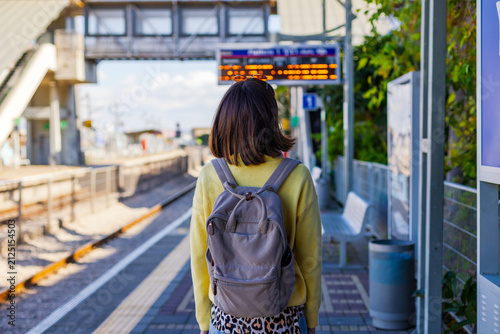 A passenger is waiting for a train. A stylish young woman is waiting for a train on the platform.