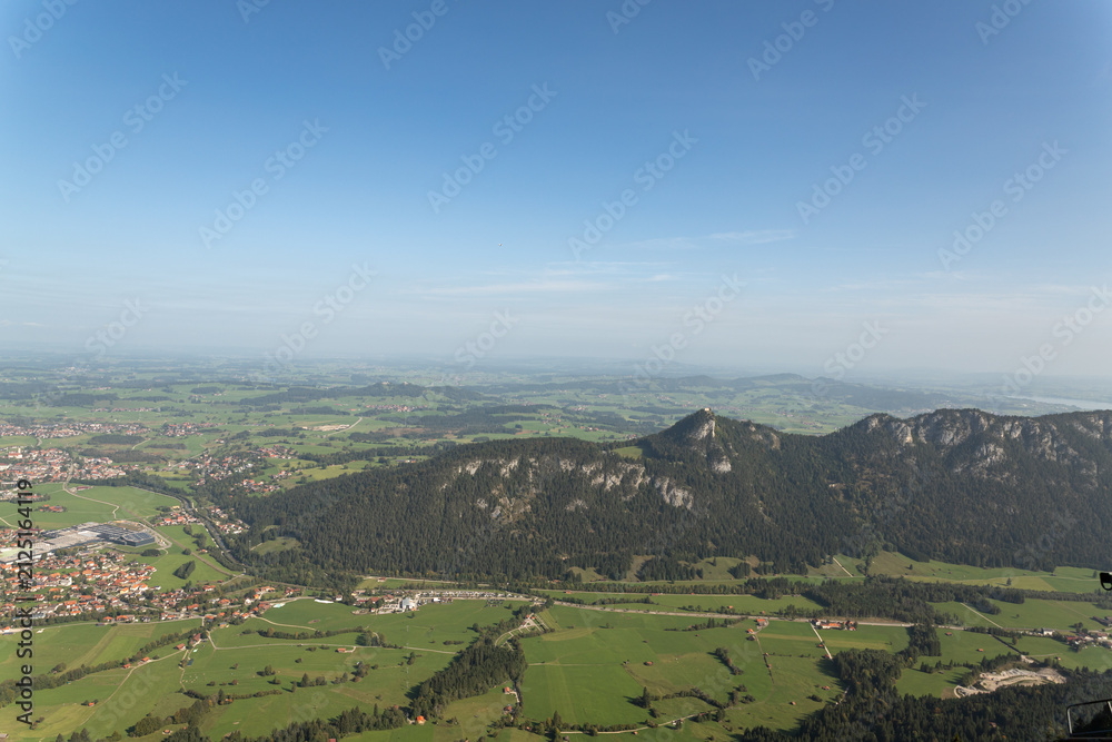 Fototapeta premium Wide alpine valley with town fields and distant mountains