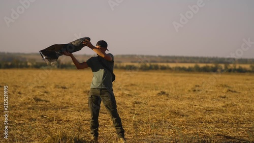 man UAV pilot with plane drone in hands preparing to launch drone in field at summer evening. preflight check. technology and engineering in modern warfare.