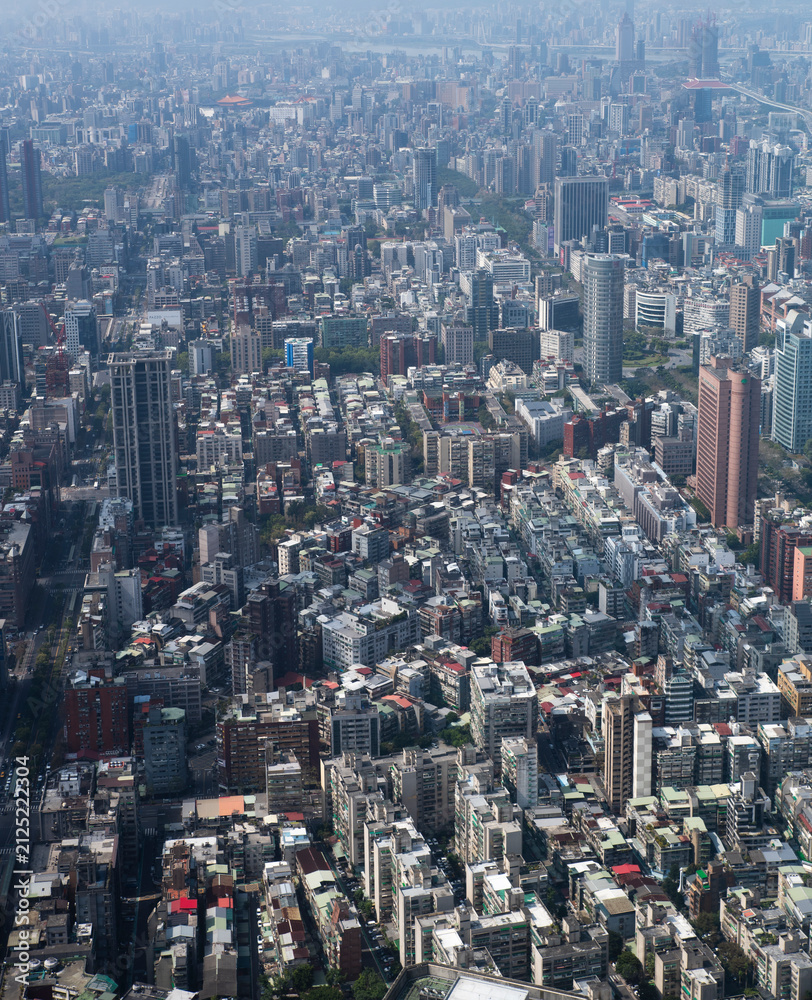 Fototapeta premium Vertical aerial view of Taipei city from Taipei 101 observatory, showing densely packed residential and commercial buildings stretching across the Taiwanese capital into the hazy distance.